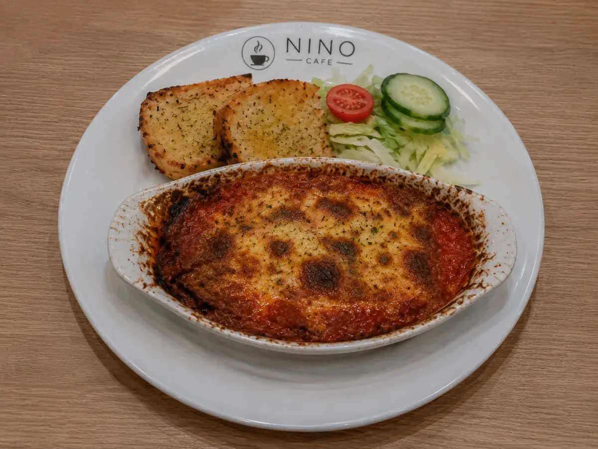 Homemade lasagne baked in its dish, with garlic bread and side salad